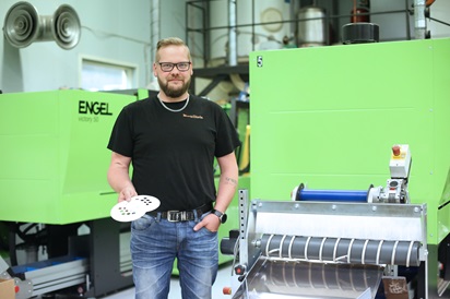 Kuvassa Antti Viitala poseeraa muovialan yrityksen sisätiloissa. Taustalla muovikappaleiden tuotantolaitteita.