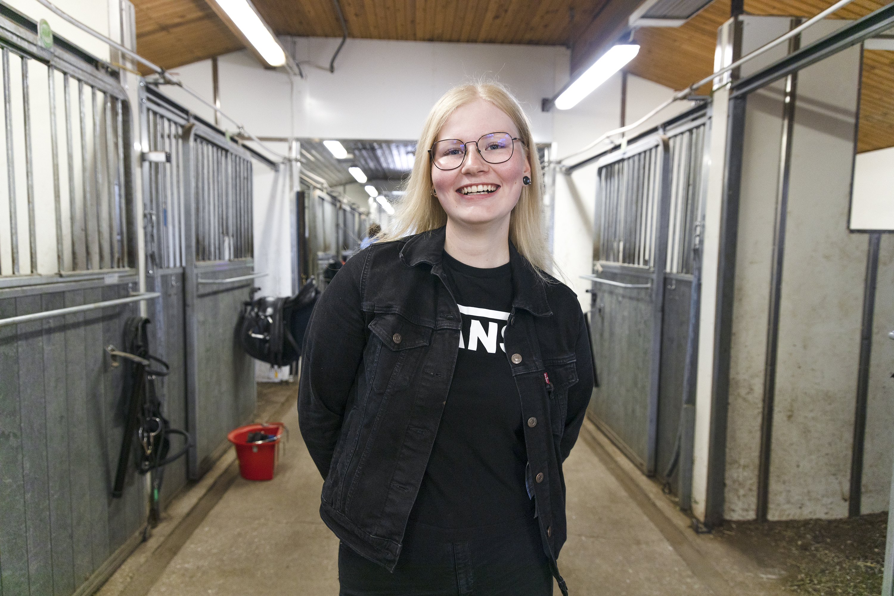 Kuvassa hevosalan opiskelija Heli Haapasalo poseeraa tallin käytävällä seisten.