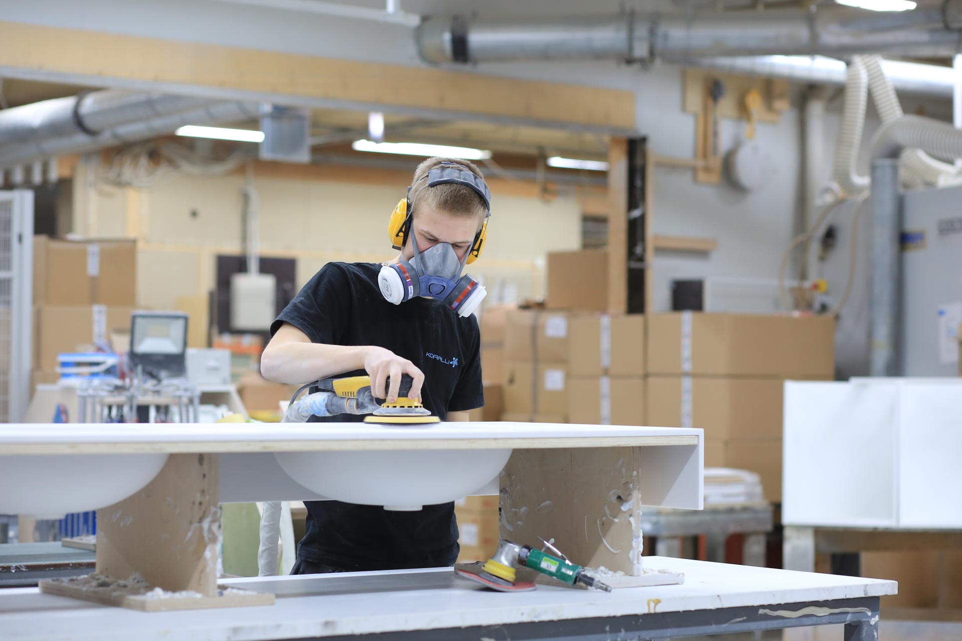 Kuvassa opiskelija Iiro Hiltula hioo Corian-materiaalista tehtyä allastasoa.
