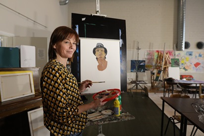 Kuvassa Kälviä Artsissa opiskeleva Elise Zoon poseeraa maalaustaulun edessä. Paperille hän on maalannut miehen kasvot.