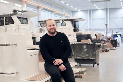 Kuvassa yrittäjä Simon Lindkvist poseeraa tuotantohallissa istuen.