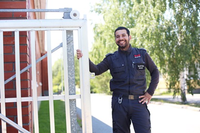 Kuvassa vartijaksi valmistunut Mohammed Hoseini poseeraa ulkona portin vieressä.