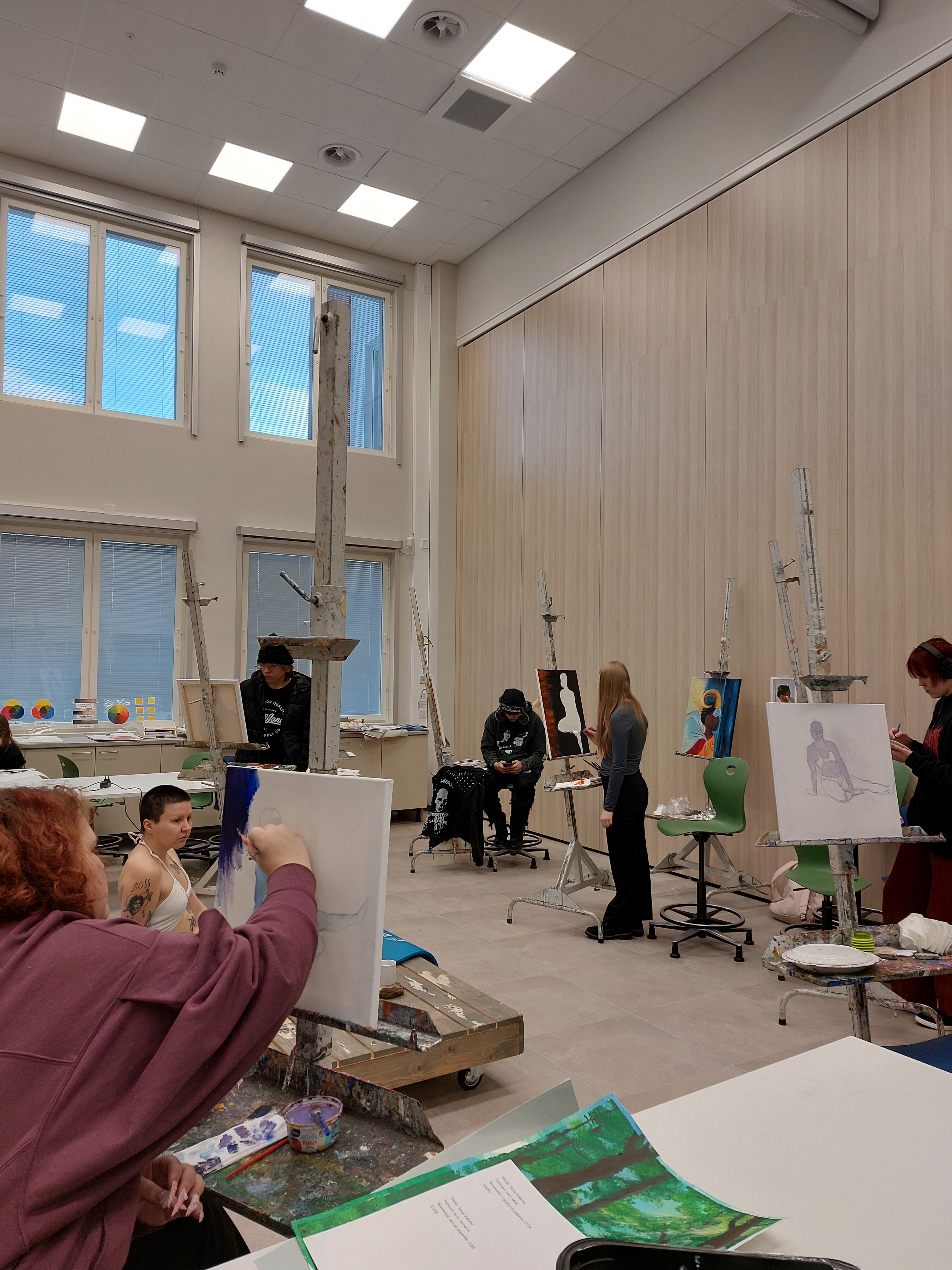 Opiskelijat harjoittelemassa mallista piirtämistä ja maalaamista.