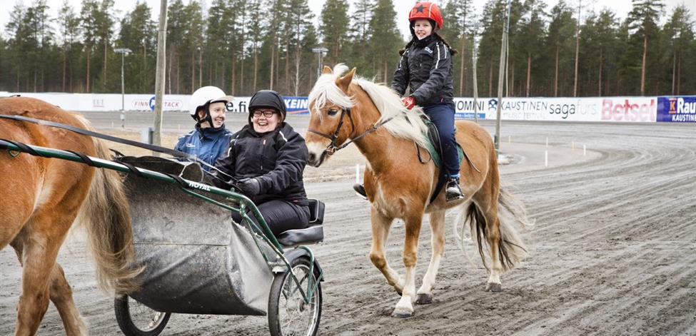 hevosala Kuvassa hevosalan opiskelijat ajavat ravihevosen kärryissä.