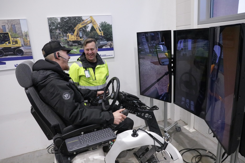 Tuomas ja opettaja Jouni Jänkä kaivinkonesimulaattorin edessä.