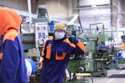 Kone- ja tuotantotekniikka-alan opiskelija poseeraa tuotantohallissa peukkua näyttäen.