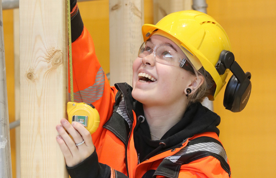 Kuvassa iloinen opiskelija mittanauhan kanssa.