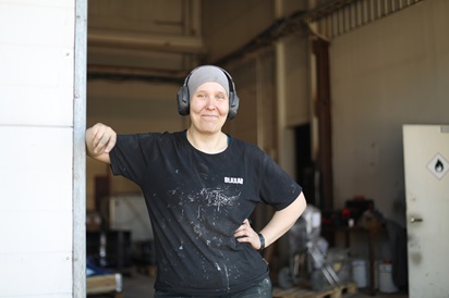 Kuvassa Blaxar Oy:lle työllistynyt Leena Alasirniö poseeraa nojaten tuotantohallin ovenkarmiin.