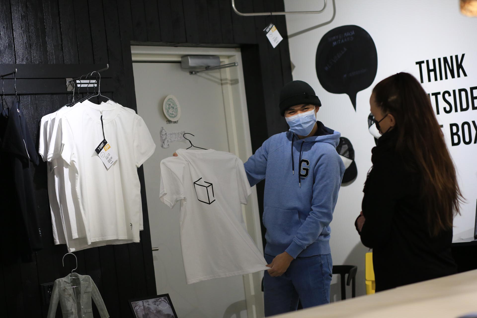Kuvassa liiketoiminnan opiskelija esittelee OG-kahviossa myytävänä olevaa t-paitaa asiakkaalle. 