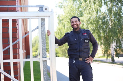 Kuvassa vartijaksi valmistunut Mohammed Hoseini poseeraa ulkona portin vieressä.