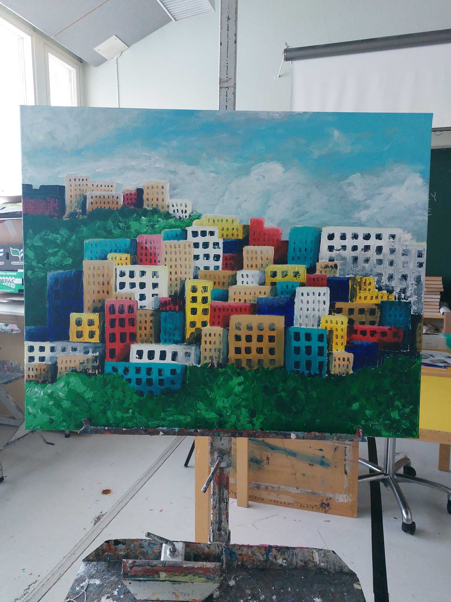 Opiskelijan maalaama kaupunkimaisema maalaustelineessä studiossa.