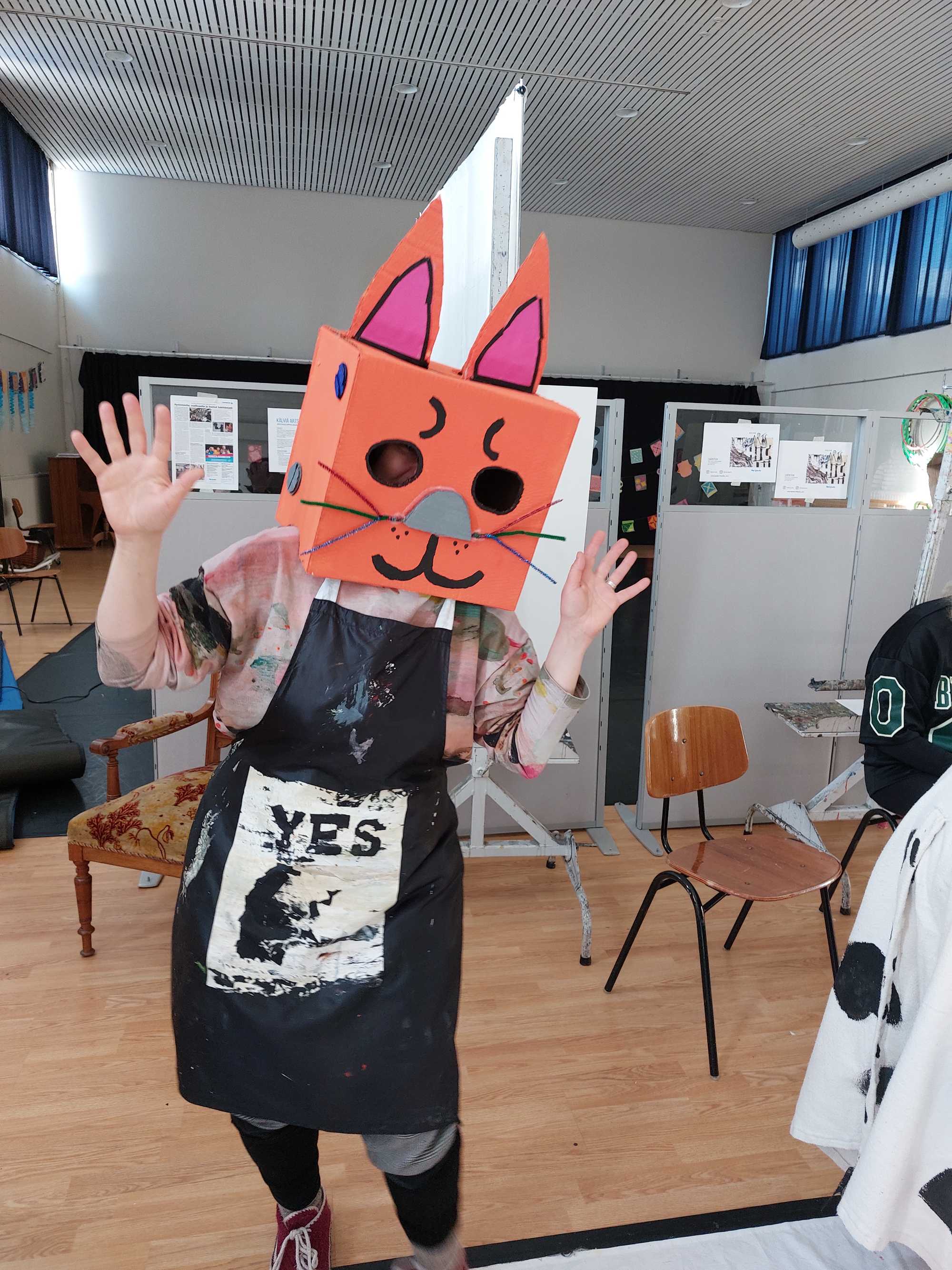 Esittävän taiteen opiskelija päässään pahvista tehty kissanaamio