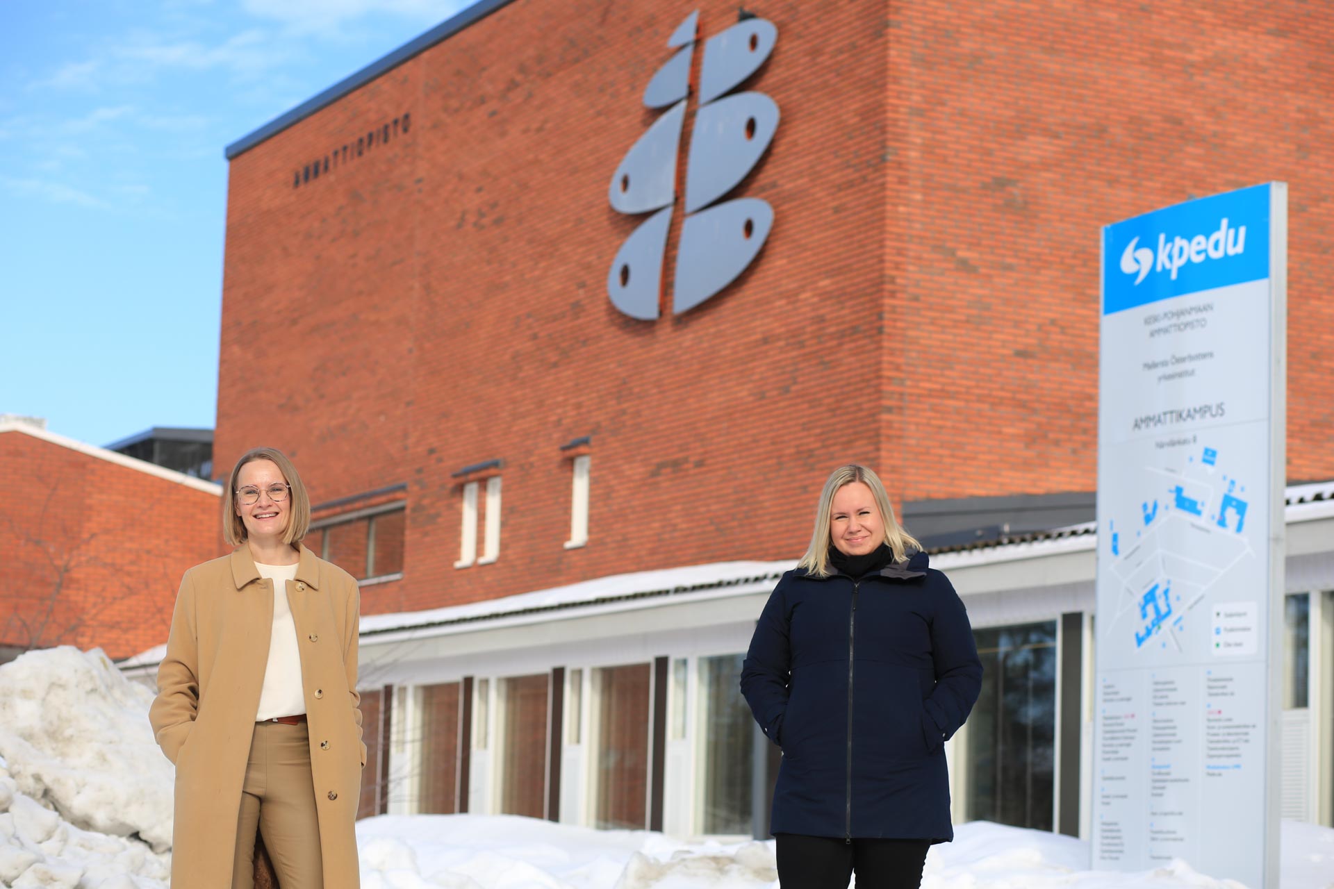 Kuvassa Annele Heikkilä ja Anu Haapasalo poseeraavat ammattiopiston ulkopuolella lumisessa maisemassa. 