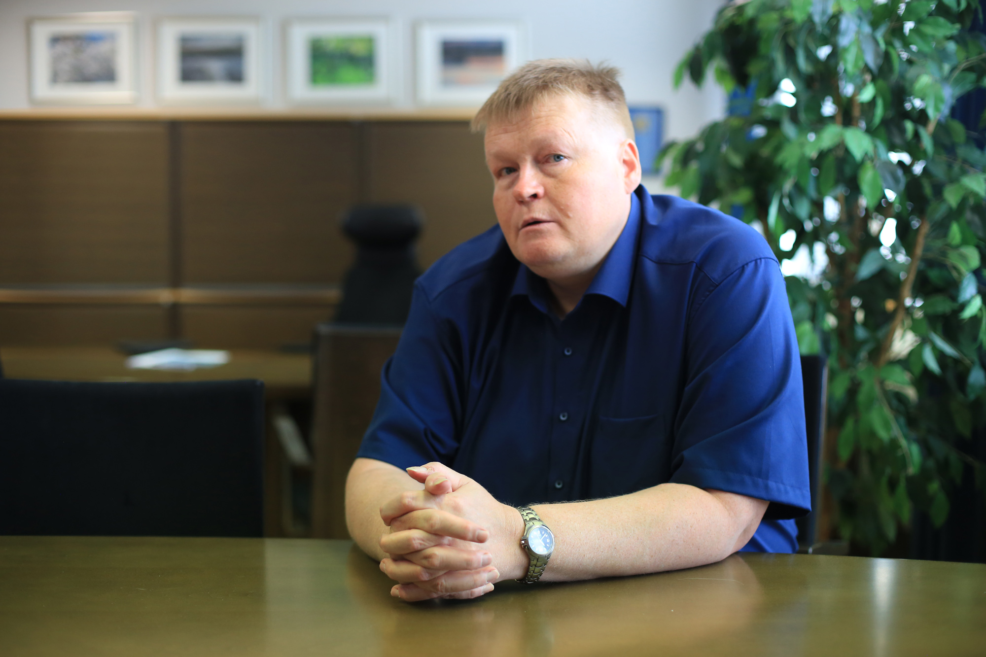 Kuvassa uusi yhtymäjohtaja poseeraa työhuoneensa pöydän äärellä.