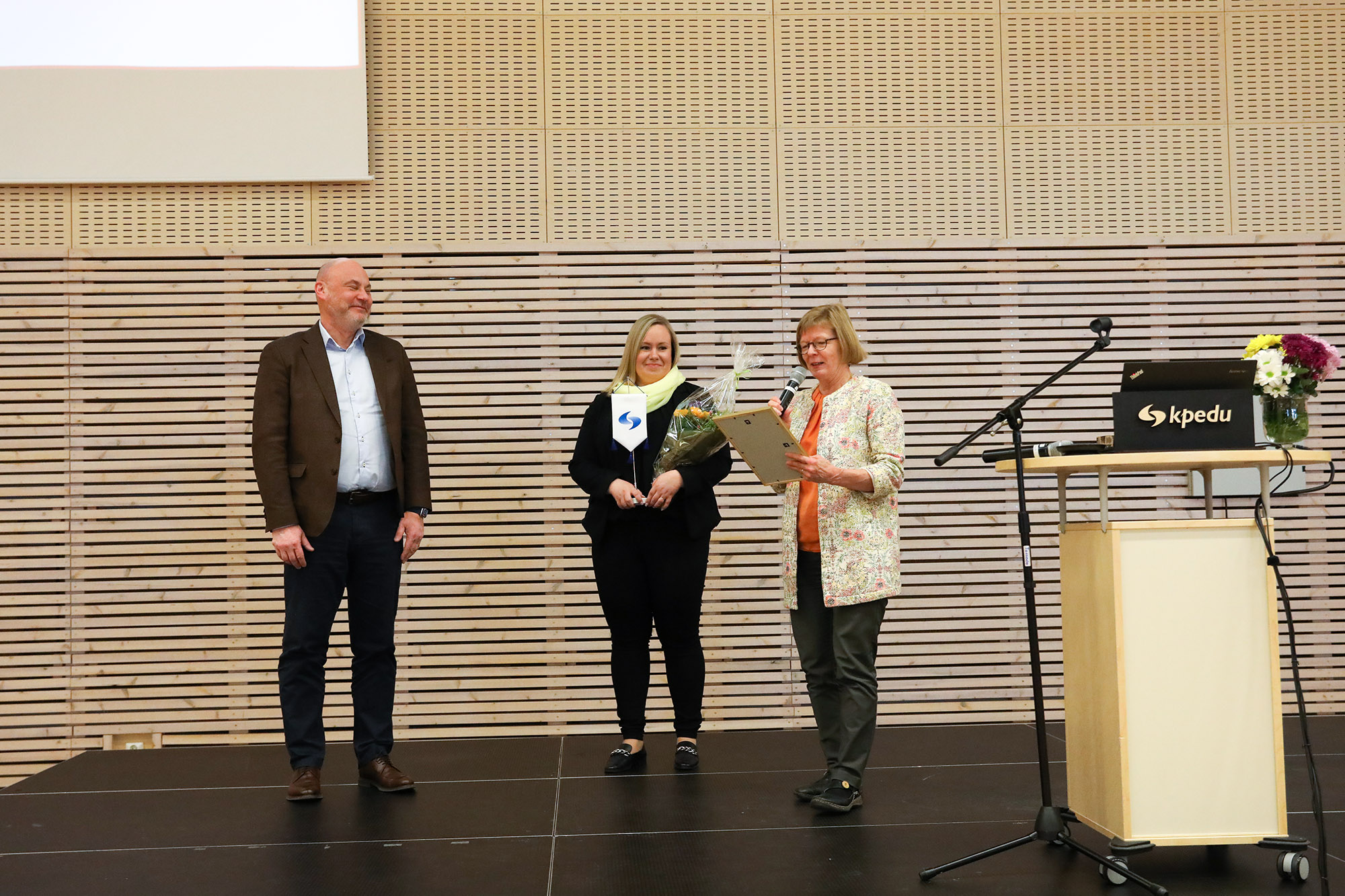 Kuvassa OsuuskKuvassa Kpedun asiakkuusjohtaja Anu Haapasalo sekä Kpedun rehtori Sirkku Purontaus lavalla luovuttamassa palkintoa Osuuskauppa KPO:n henkilöstöjohtajalle Leif Lindbergille.